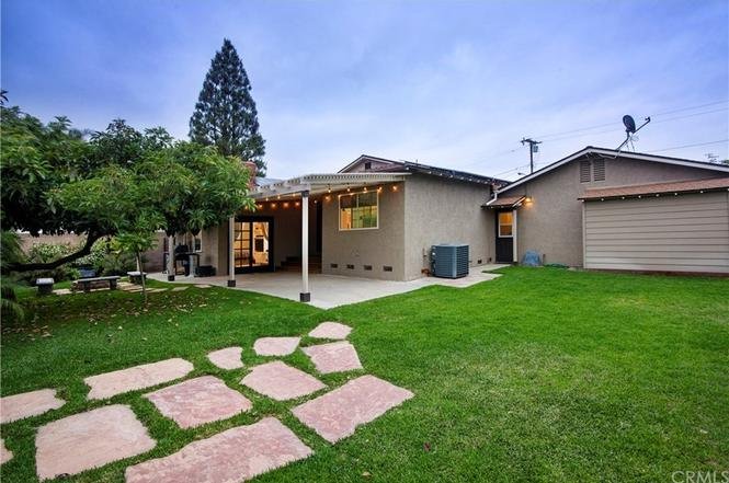 A backyard with a single-story house, covered patio