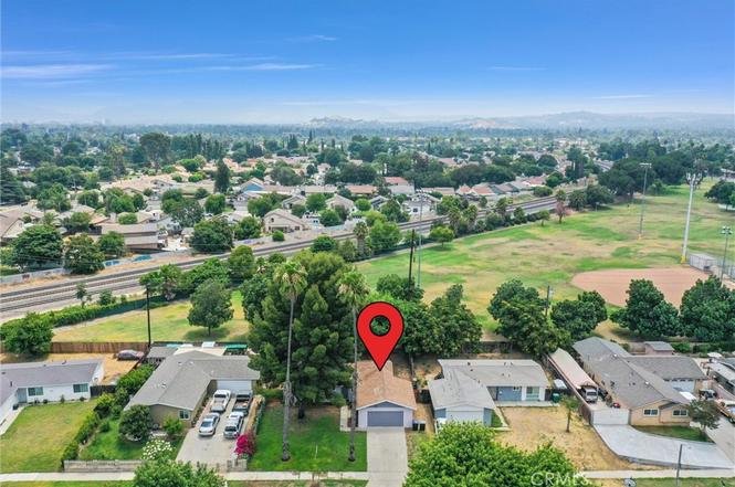 Aerial view of a suburban neighborhood featuring a single-story house with a red location pin above it